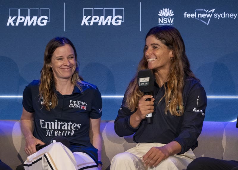 Atletas de vela durante coletiva de imprensa do SailGP com logos de patrocinadores ao fundo