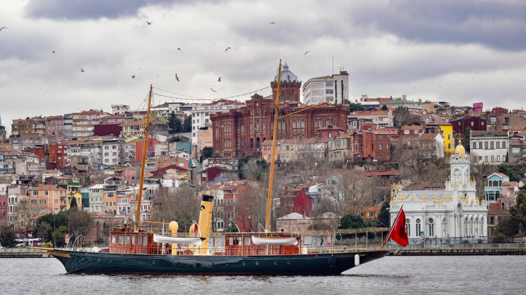 Iate a vapor Cangarda restaurado navegando no Bósforo com paisagem urbana de Istambul ao fundo