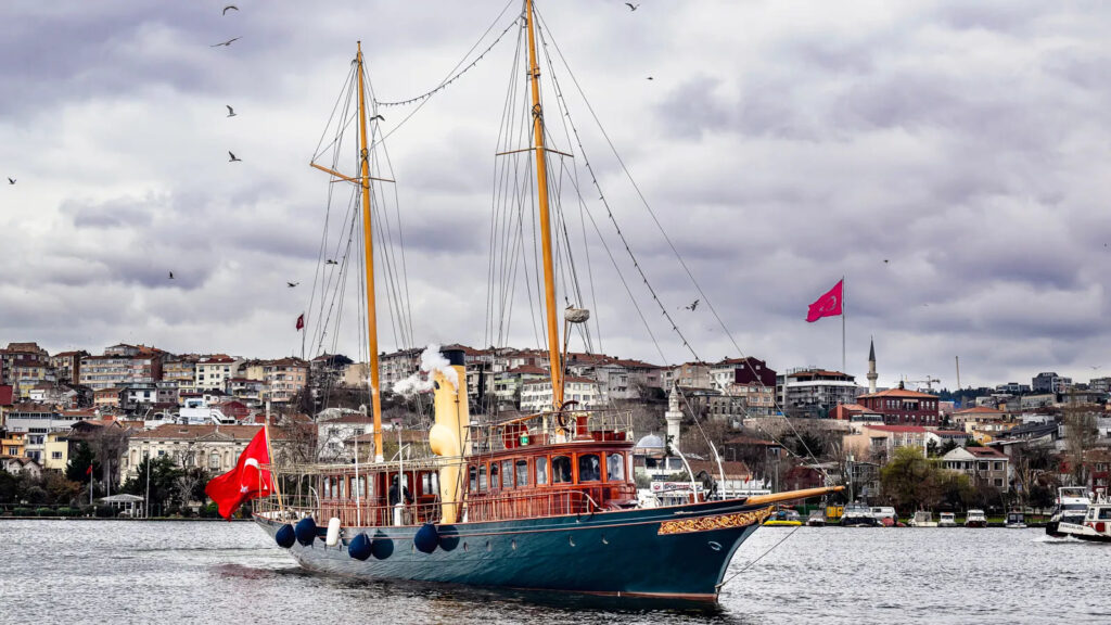 Iate a vapor Cangarda restaurado navegando em Istambul com arquitetura histórica ao fundo