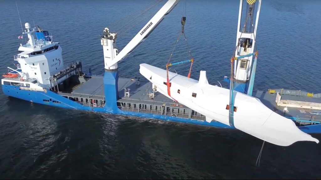 Iate a vapor histórico Cangarda sendo transportado por guindaste em navio de carga durante processo de restauração