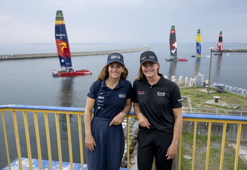 Martine Grael e Kahena Kunze posam na Baía de Guanabara com barcos de vela ao fundo durante evento no Rio de Janeiro