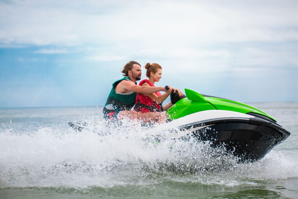 Casal pilotando jet ski em alta velocidade no mar com coletes salva-vidas, seguindo regras de segurança na navegação