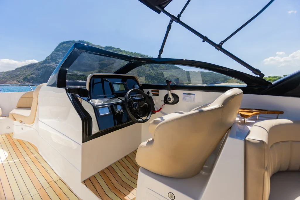 Posto de comando da lancha Coral 26 WA com painel eletrônico, volante e cockpit revestido em piso estilo teca.