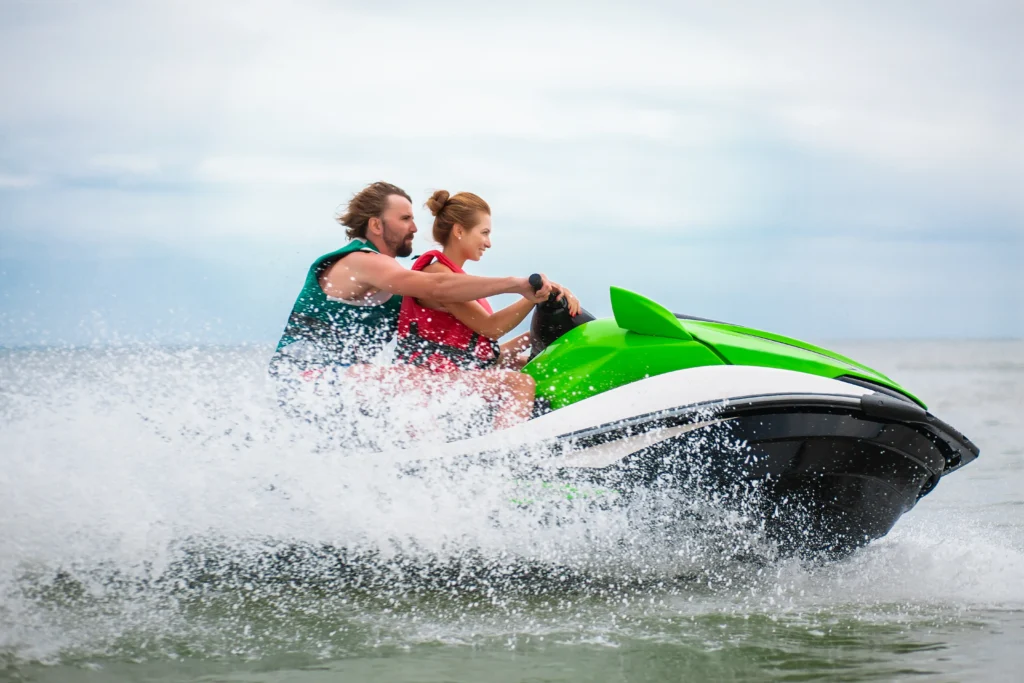 Casal andando de jet-ski em alta velocidade no mar durante passeio aquático.