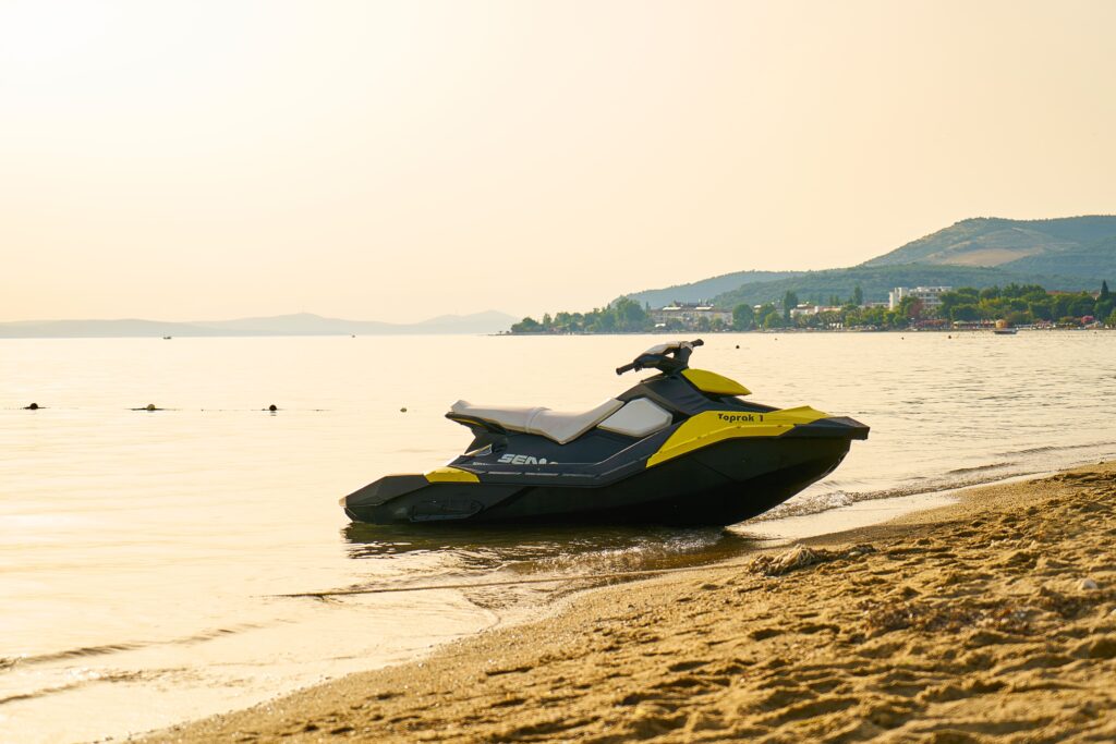 Jet ski parado na areia da praia durante pôr do sol no litoral, ilustrando uso de moto aquática com novas regras de segurança