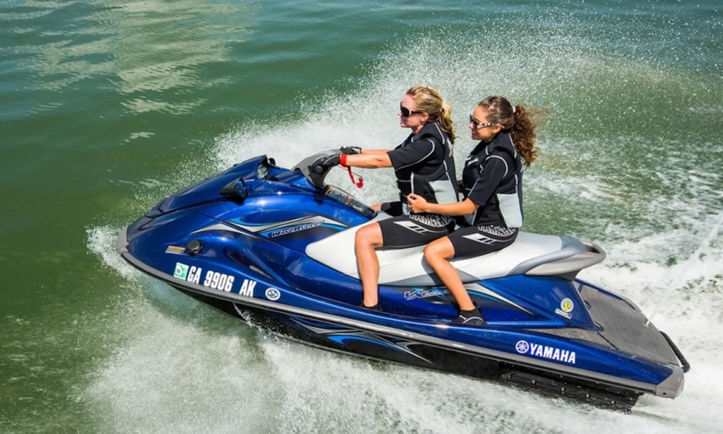 Duas pessoas andando de Yamaha WaveRunner azul na água