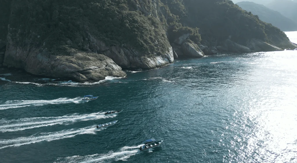 Barcos navegam entre paredões rochosos da Ponta da Juatinga, no litoral de Paraty
