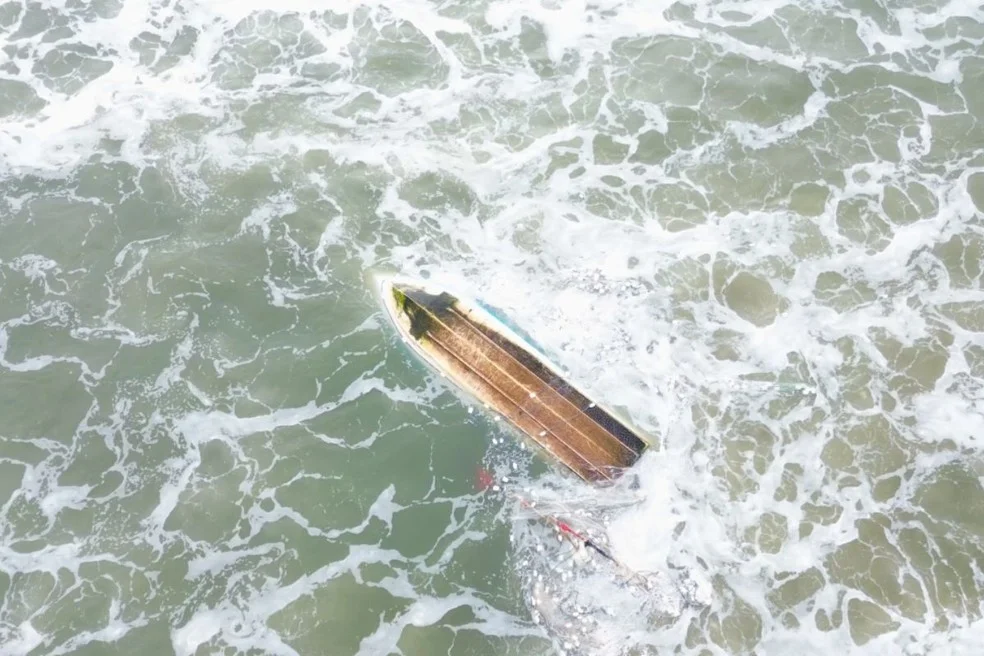 Barco virado no mar durante resgate de pescadores em Peruíbe no litoral de São Paulo.