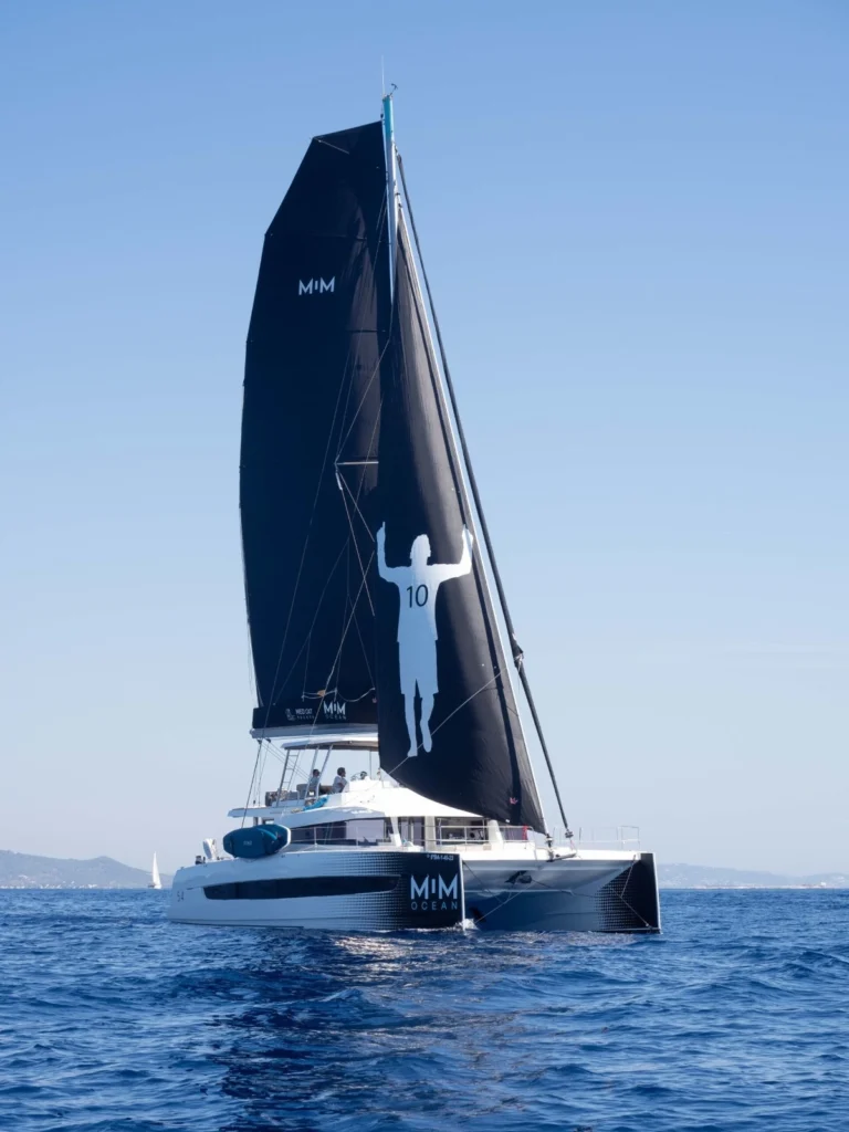 Catamarã Bali 5.4 com velas pretas personalizadas com a silhueta de Lionel Messi.