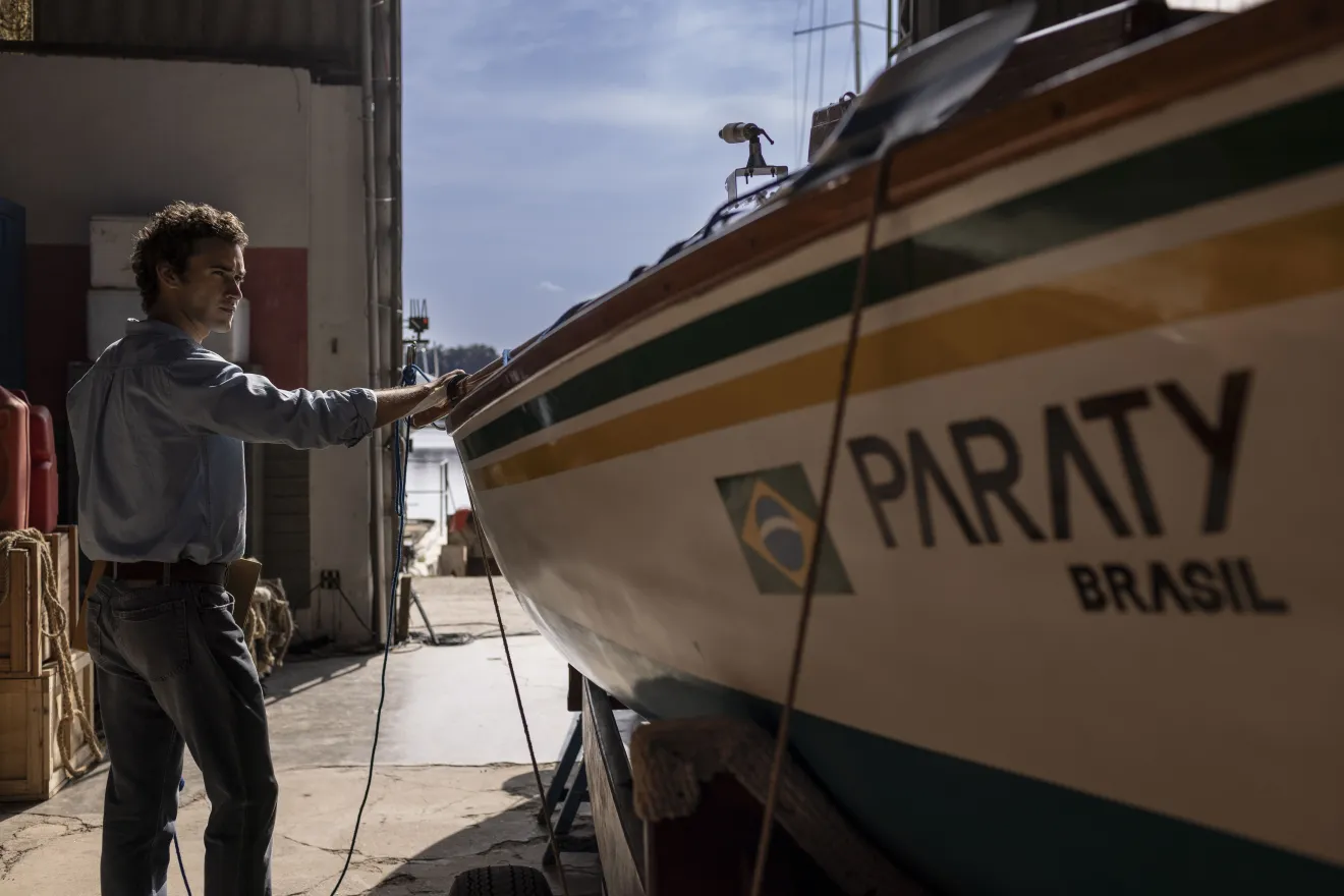 Cena do filme 100 Dias mostra personagem inspirado em Amyr Klink ao lado da embarcação utilizada na travessia do Atlântico Sul.