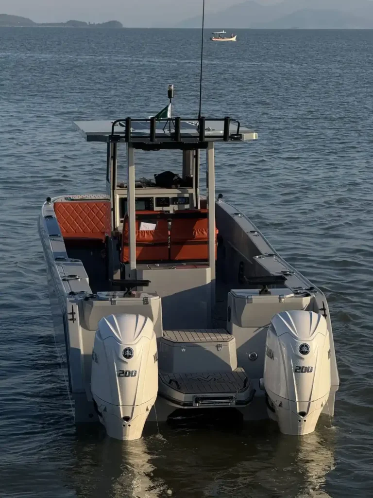 Lancha de pesca com console central e dois motores Yamaha de 200 hp ancorada em águas calmas, com amplo deck para circulação dos pescadores.