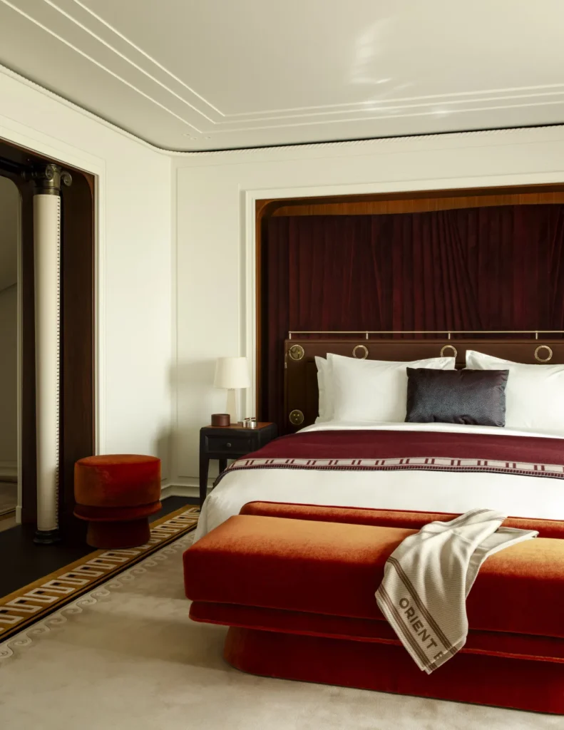 Suíte de luxo do Orient Express Corinthian com decoração sofisticada em tons de vermelho e detalhes Art Déco.