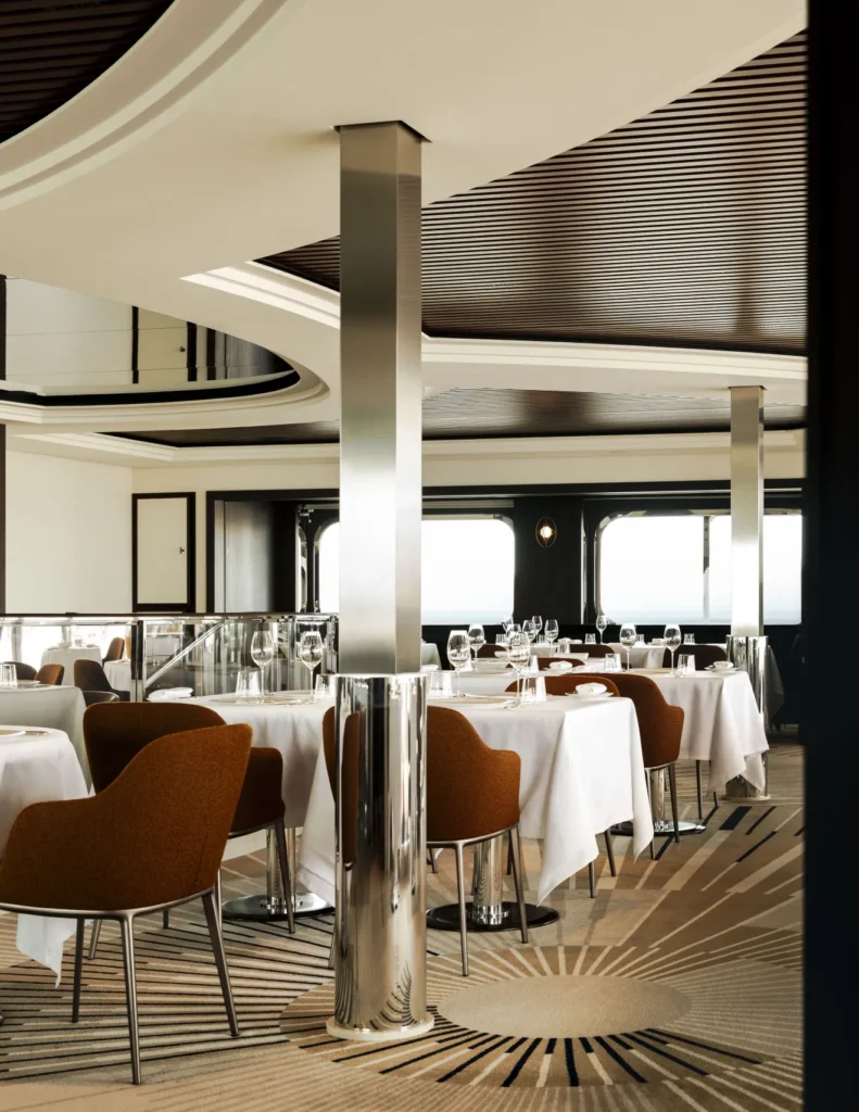 Restaurante de luxo a bordo do Orient Express Corinthian com decoração elegante e vista para o mar.