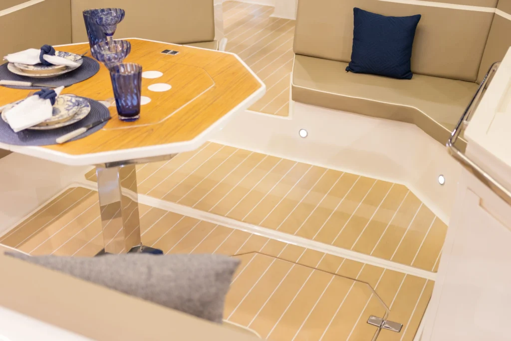 Piso para barco Thermo Deck Classic da Kapazi Náutica com acabamento que reproduz madeira natural e frisos brancos em área de convivência da embarcação.