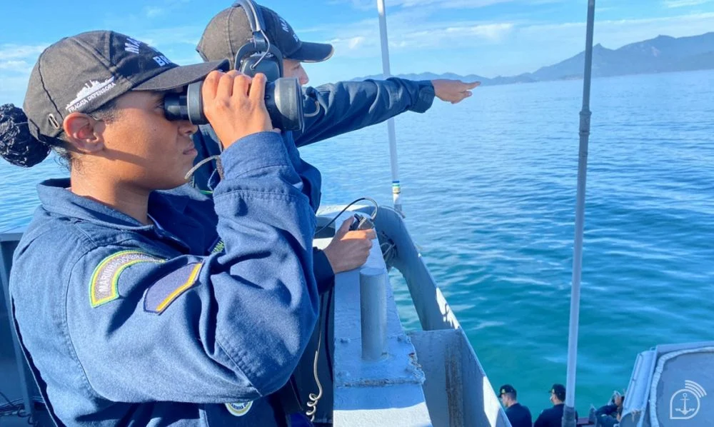 Militar da Marinha do Brasil utiliza binóculo durante atividade de navegação no mar.