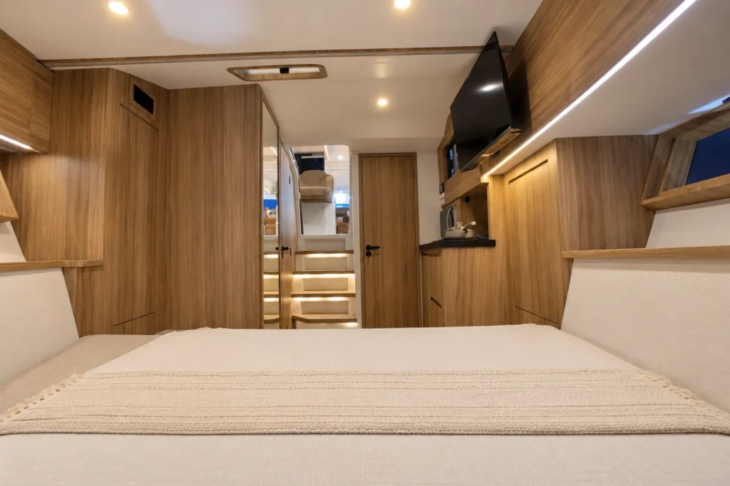 Cabine interna da Coral 40 Sea Breeze com cama de casal, armários de madeira, televisão e iluminação embutida.