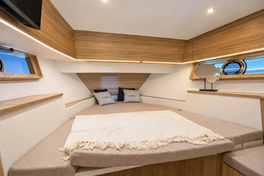 Camarote da Coral 40 Sea Breeze com cama de casal, almofadas, armários superiores de madeira e janelas laterais circulares.