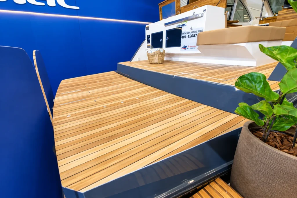 Plataforma de popa da Coral 40 Sea Breeze com revestimento em teca, superfície ampla e degrau de acesso à área superior.