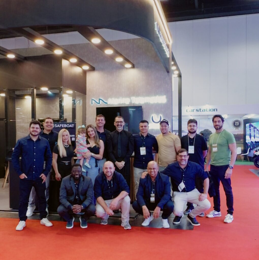 Equipe da JRG Corp reunida durante o São Paulo Boat Show 2026. O grupo é formado por pessoas em pé e sentadas, posando para uma foto no corredor do evento.