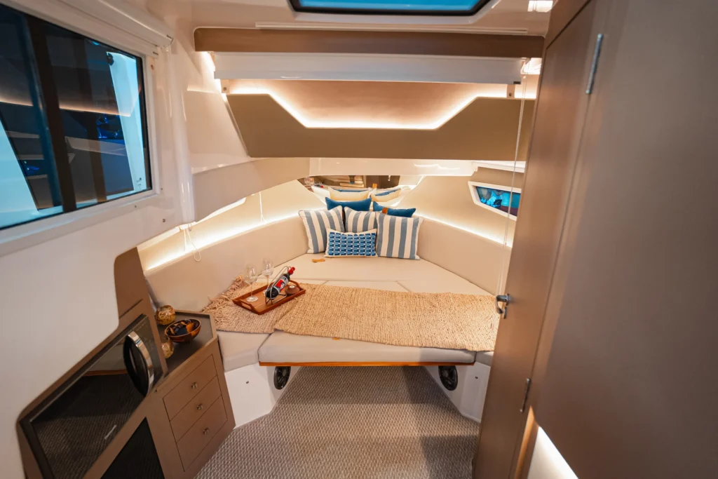 Cabine da Focker 388 GT com cama, almofadas decorativas e iluminação indireta.