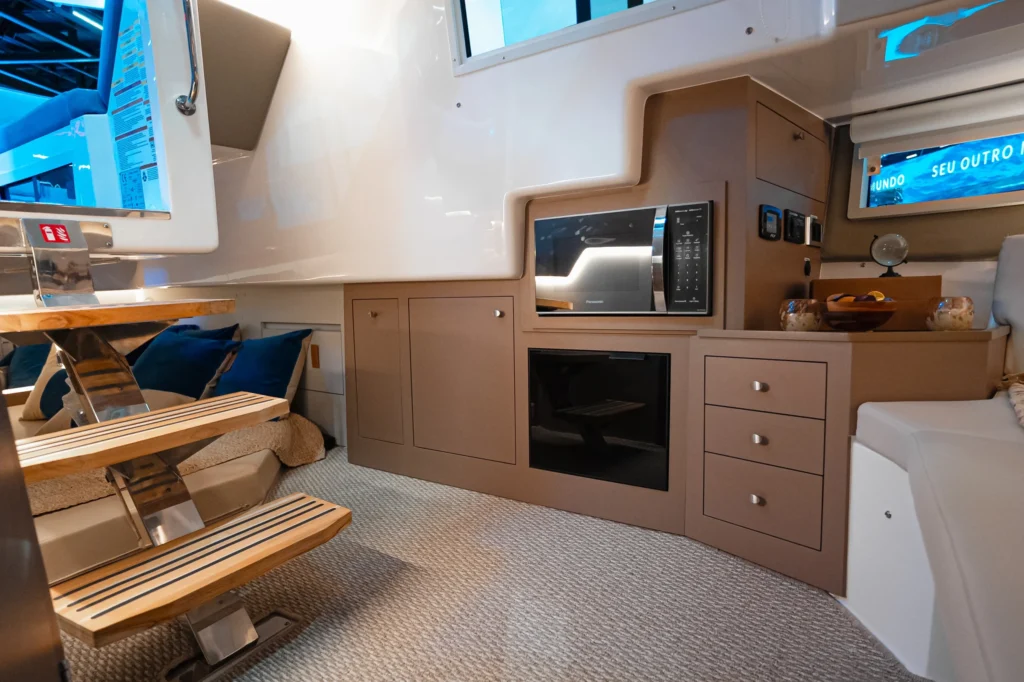 Área interna da Focker 388 GT com armários, micro-ondas, forno e escada de madeira.